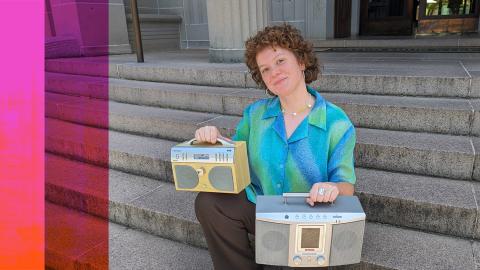 A woman sits on concrete steps holding two portable radios, one on each knee