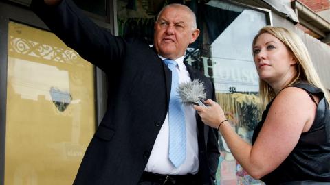 Policeman Ron Iddles with journalist Rachel Brown standing in front of a shop on a Melbourne street. 