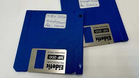 Two floppy disks with a handwritten label on them identifying them as a Neighbours video game.