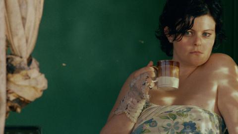 Genevieve Lemon holding a coffee mug and looking out the window in a still from the film Sweetie.