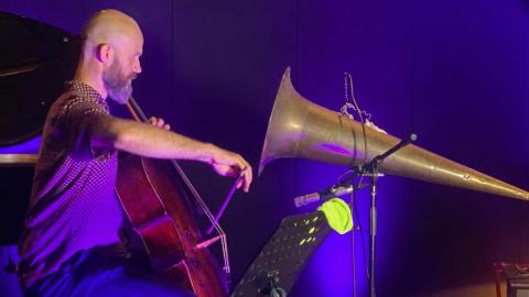 Christopher Pidcock plays the cello into a large gramophone horm, to record a wax cylinder.