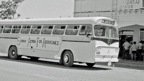 A large bus pictured from the side. It has a sign on the side that reads 'Student Action For Aborigines'.
