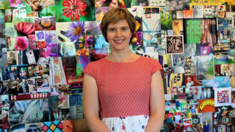 Beth Taylor standing in front of her exhibition of 1000 photos on the topic of 'home'