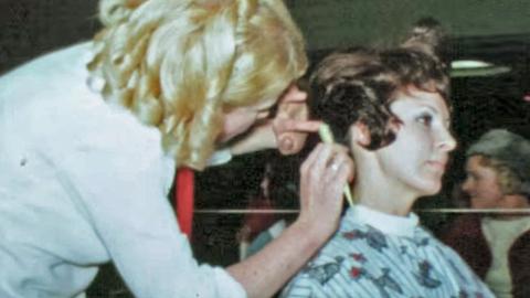 Woman cutting another woman's hair at hair-dressing competition, circa 1960.