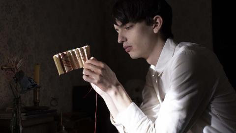 Kodi Smit-McPhee folding paper to make it into decorative flowers in a scene from The Power of the Dog