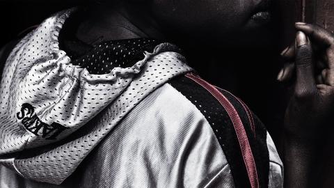 A young Aboriginal man wearing an athletics hoodie and looking away from the camera