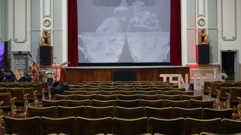 The interior of an old theatre. You can see the screen in the centre and rows of chairs facing it.