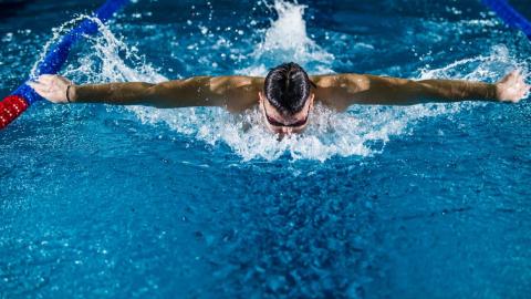 A man swimming a butterfly stroke in an Olympic pool