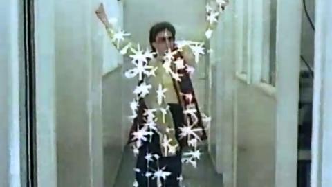 Frame capture of a woman in a hallway with superimposed starbursts across her body