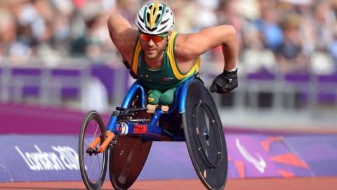 Kurt Fearnley Paralympics article hero Wheelchair racer Kurt Fearnley is captured racing at the London 2012 Paralympics. A packed stadium is blurred behind him.