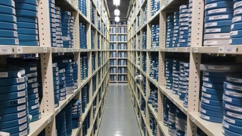 Rows of shelving stacked with film canisters in the NFSA vaults