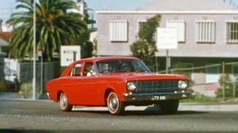 How to Drive A red 1968 Ford XT Falcon drives along a suburban street.