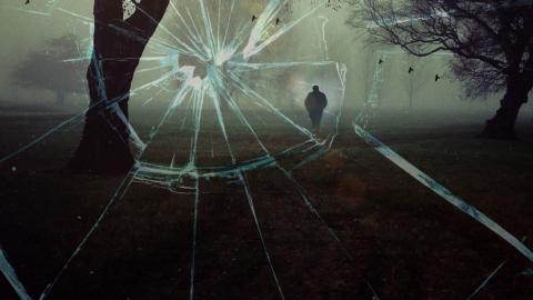 Australian True Crime Mysteries hero image View from a window that has been shattered showing a dark, shadowy figure of a man walking through a grassy field between some trees.