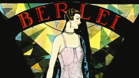 Berlei: glass slide no. 34, controlette 6181 A colour glass slide showing an illustration of a woman wearing a pink Berlei foundation garment with a necklace and earrings. The shapes, font (it says 'berlei') and triangular design elements are influenced by art deco.