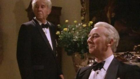 Sir John Kerr (John Meillon) standing and Prime Minister Gough Whitlam (Max Phipps) seated in formal attire