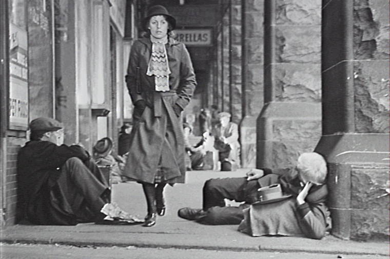 Film still of Caddie walking past homeless men at Central Station, Sydney durng the Depression.