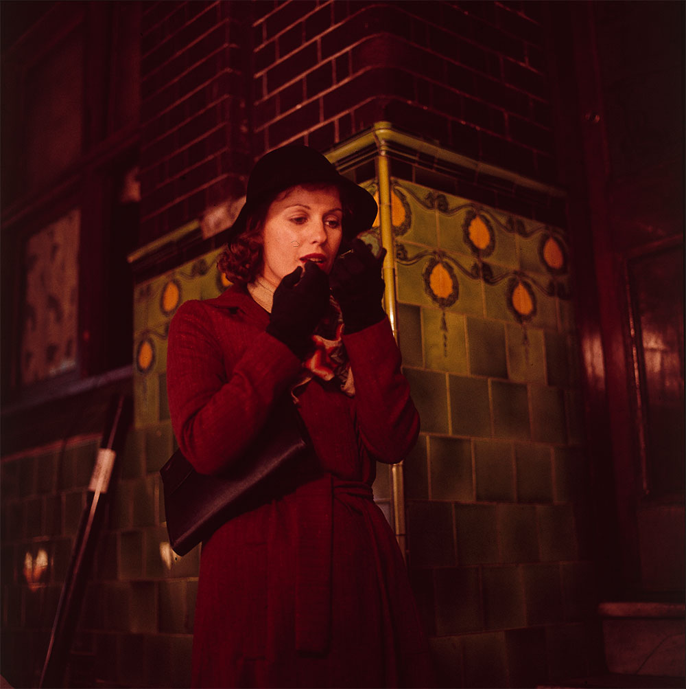 Film still of Helen Morse as Caddie applying lipstick as she walks along a street at night.