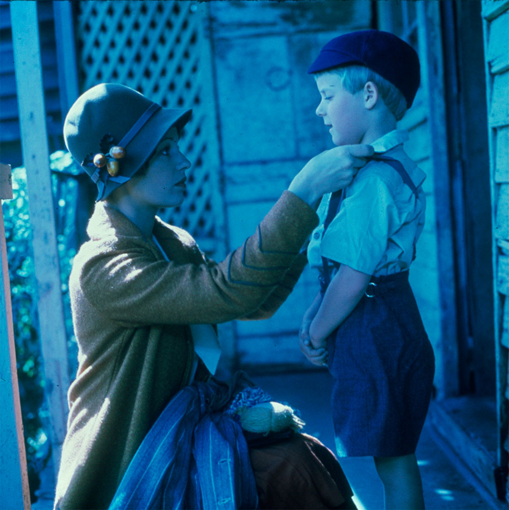 Film still of Helen Morse as Caddie with Sean Hinton as her on-screen son, Terry. Caddie crouching down to straighten Terry